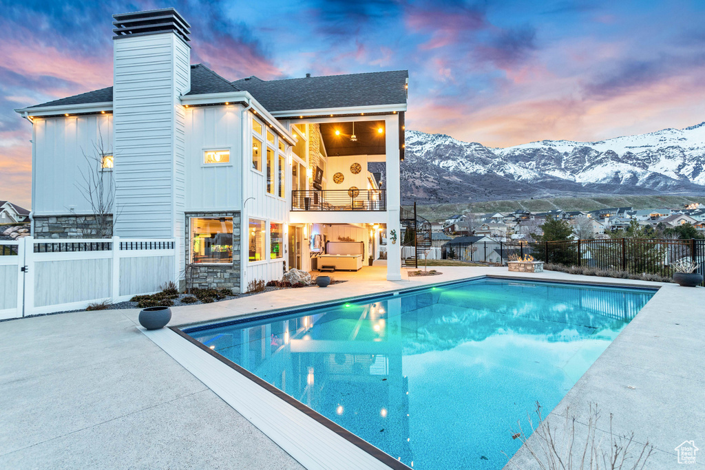 Pool at dusk featuring a mountain view and a patio area