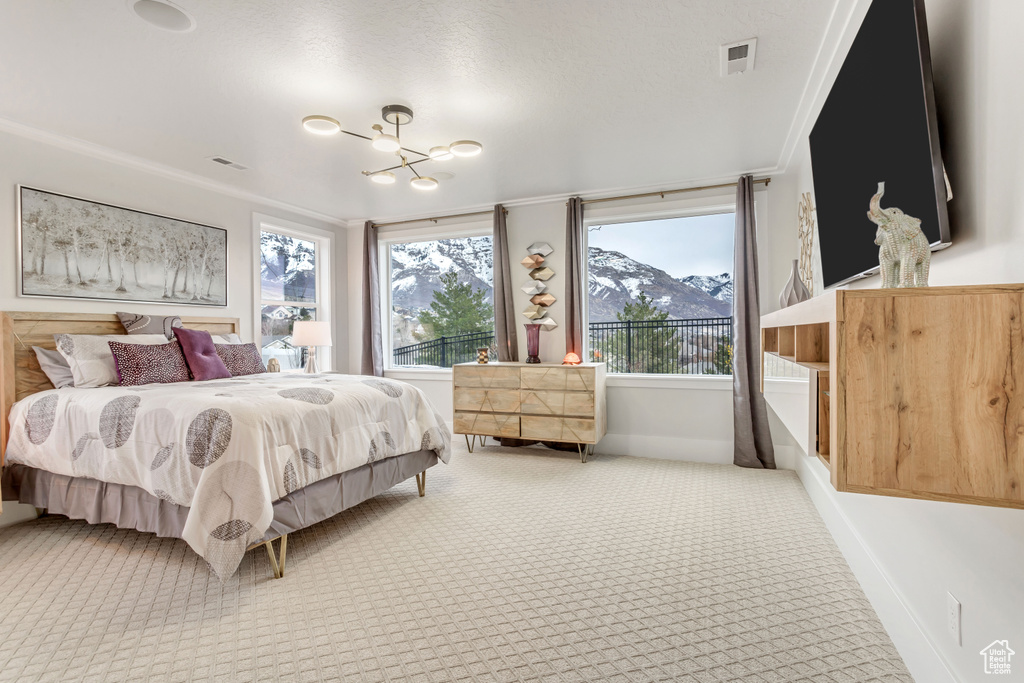 Carpeted bedroom with an inviting chandelier, crown molding, and a mountain view