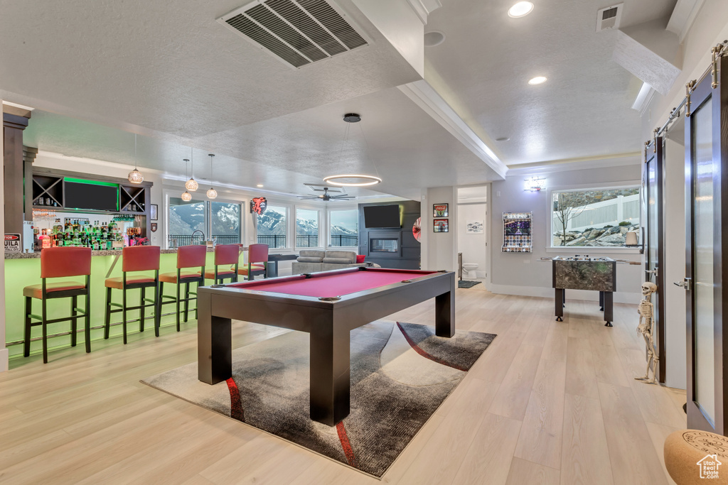 Playroom with billiards, ceiling fan, light hardwood / wood-style floors, and indoor bar