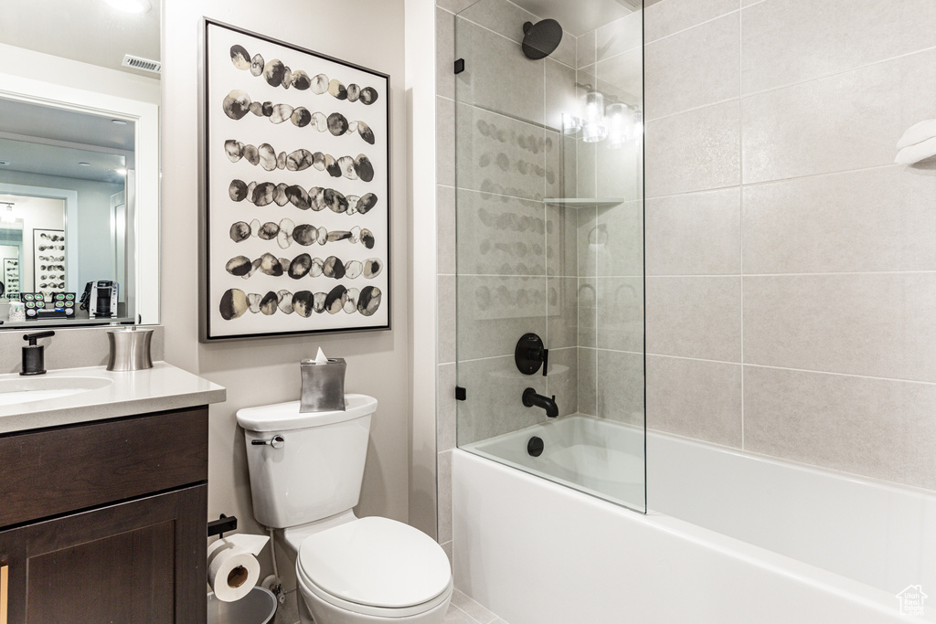Full bathroom featuring tiled shower / bath combo, toilet, and vanity with extensive cabinet space