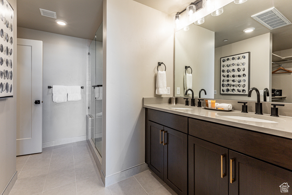 Bathroom with tile flooring, a shower with shower door, and double sink vanity