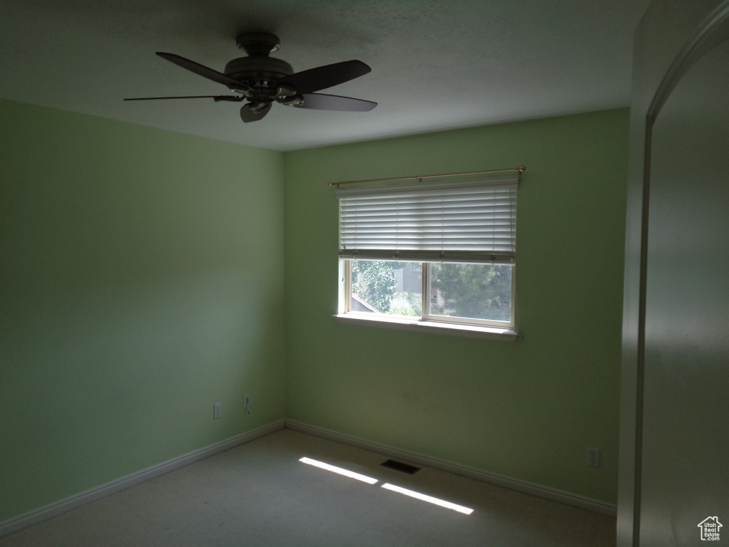 Empty room featuring ceiling fan and carpet floors
