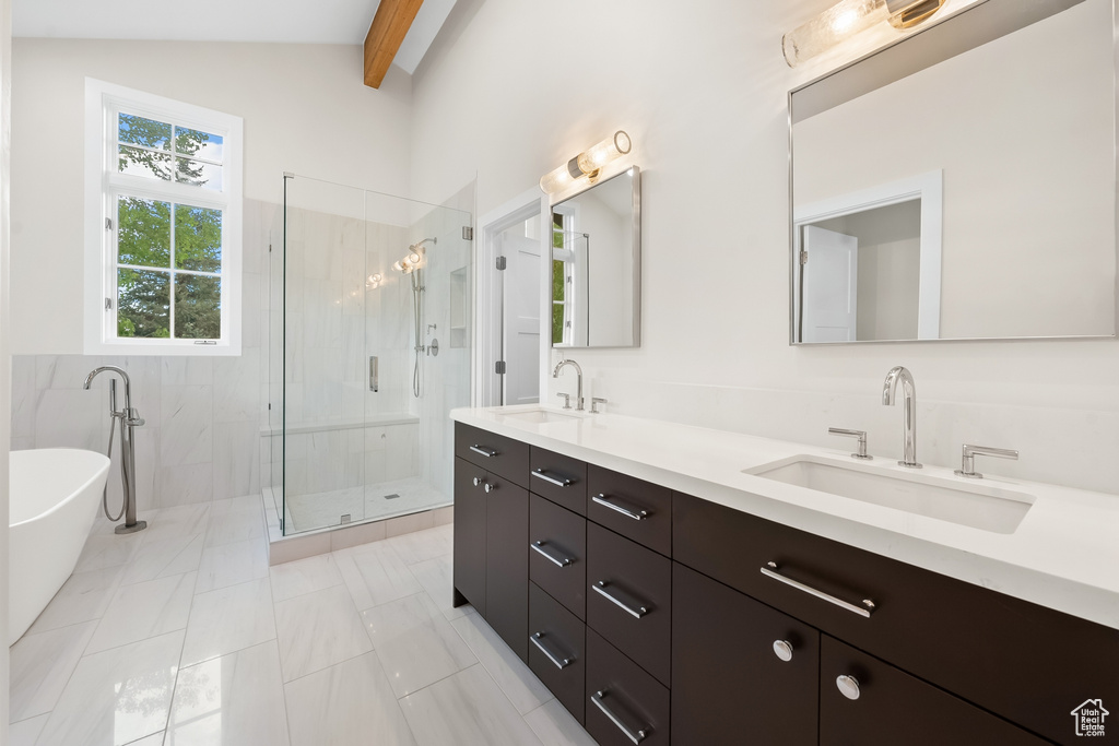 Bathroom with dual sinks, separate shower and tub, vanity with extensive cabinet space, tile floors, and vaulted ceiling with beams