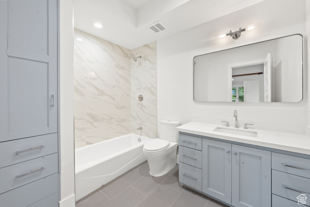 Full bathroom featuring tiled shower / bath combo, toilet, tile flooring, and oversized vanity