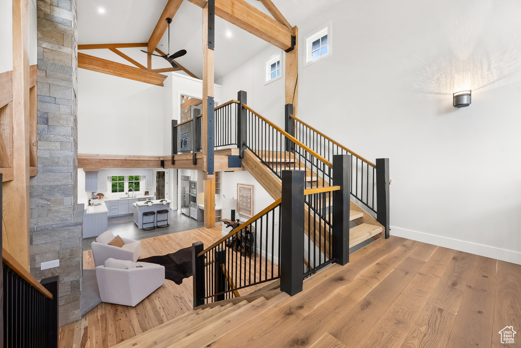 Staircase with high vaulted ceiling, beamed ceiling, and light hardwood / wood-style floors