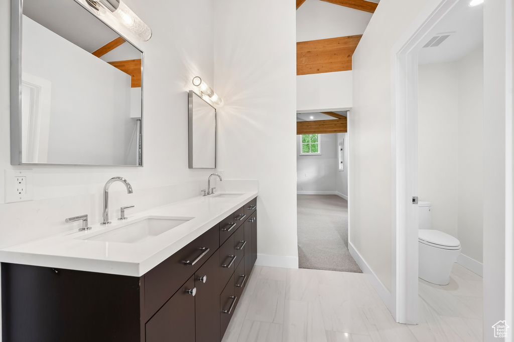 Bathroom with large vanity, toilet, dual sinks, and tile flooring