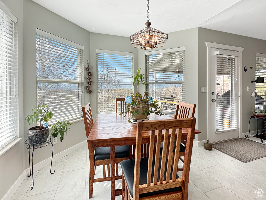 Dining space with a healthy amount of sunlight, a notable chandelier, and light tile floors