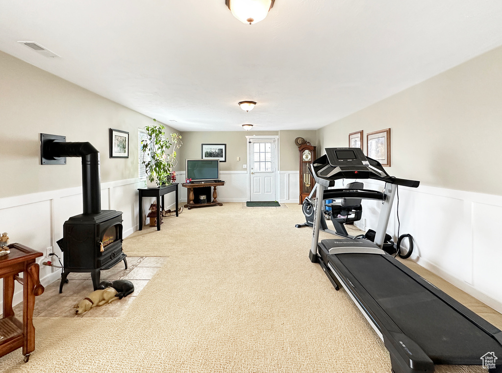 Workout room with light carpet and a wood stove