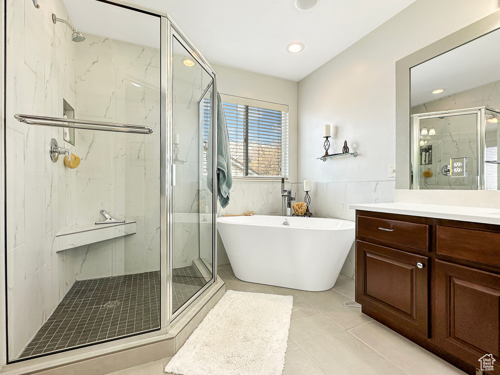 Bathroom featuring tile walls, tile floors, vanity, and plus walk in shower