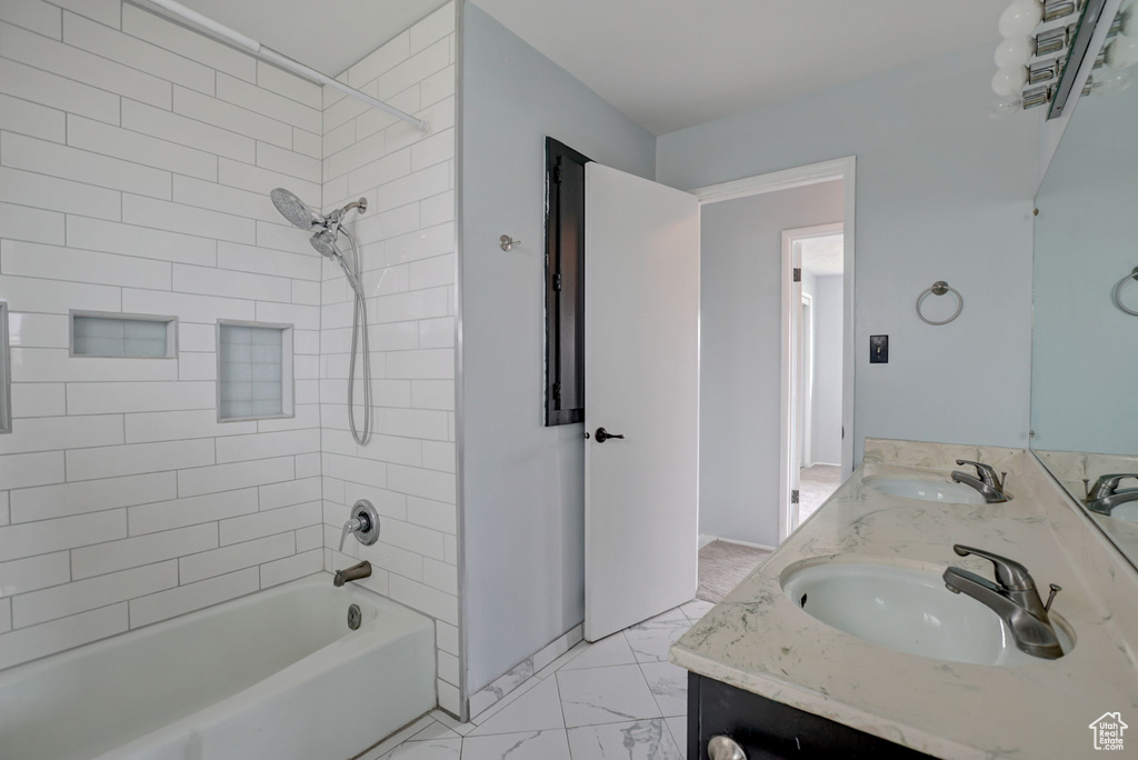 Bathroom featuring tiled shower / bath combo, tile flooring, vanity with extensive cabinet space, and dual sinks