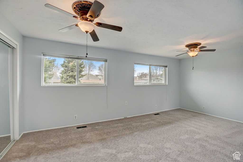 Spare room featuring plenty of natural light, carpet flooring, and ceiling fan