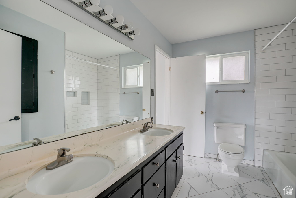 Full bathroom with double sink, a wealth of natural light, toilet, and tiled shower / bath