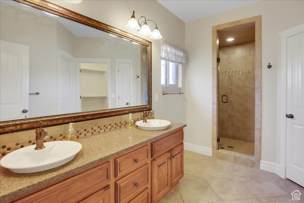 Bathroom featuring tile floors, dual vanity, and walk in shower