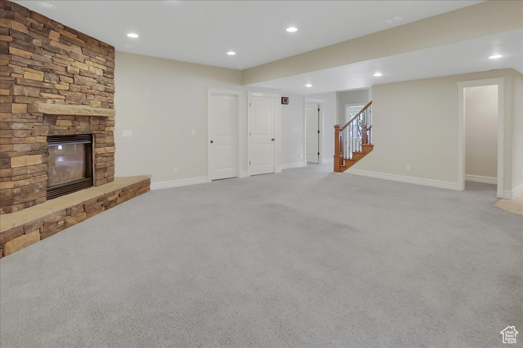 Unfurnished living room featuring light carpet and a stone fireplace