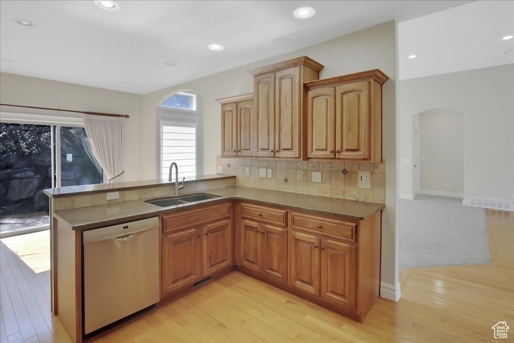Kitchen with sink, tasteful backsplash, dishwasher, kitchen peninsula, and light hardwood / wood-style floors