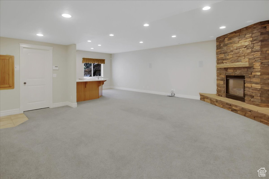 Unfurnished living room featuring a fireplace and light colored carpet