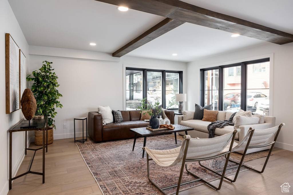 Living room featuring beamed ceiling, plenty of natural light, and light wood-type flooring