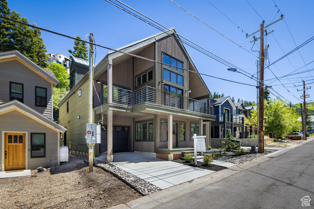 View of front of home featuring a garage and a balcony