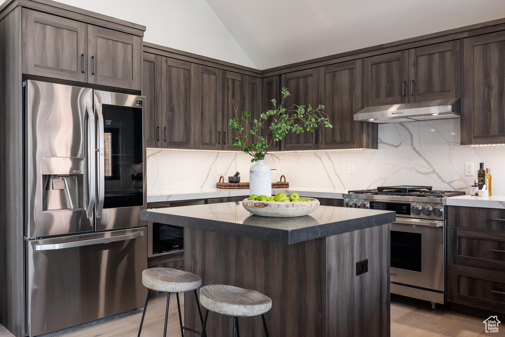 Kitchen featuring stainless steel appliances, tasteful backsplash, light hardwood / wood-style floors, and a kitchen island