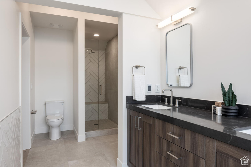 Bathroom with tiled shower, tile floors, vanity, and toilet