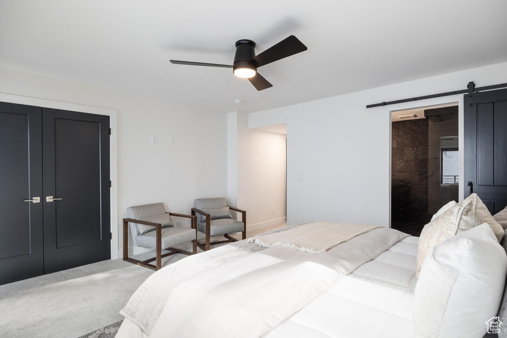 Bedroom featuring a closet, a barn door, ceiling fan, and carpet floors