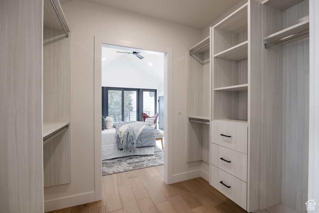 Walk in closet with ceiling fan, light hardwood / wood-style flooring, and lofted ceiling