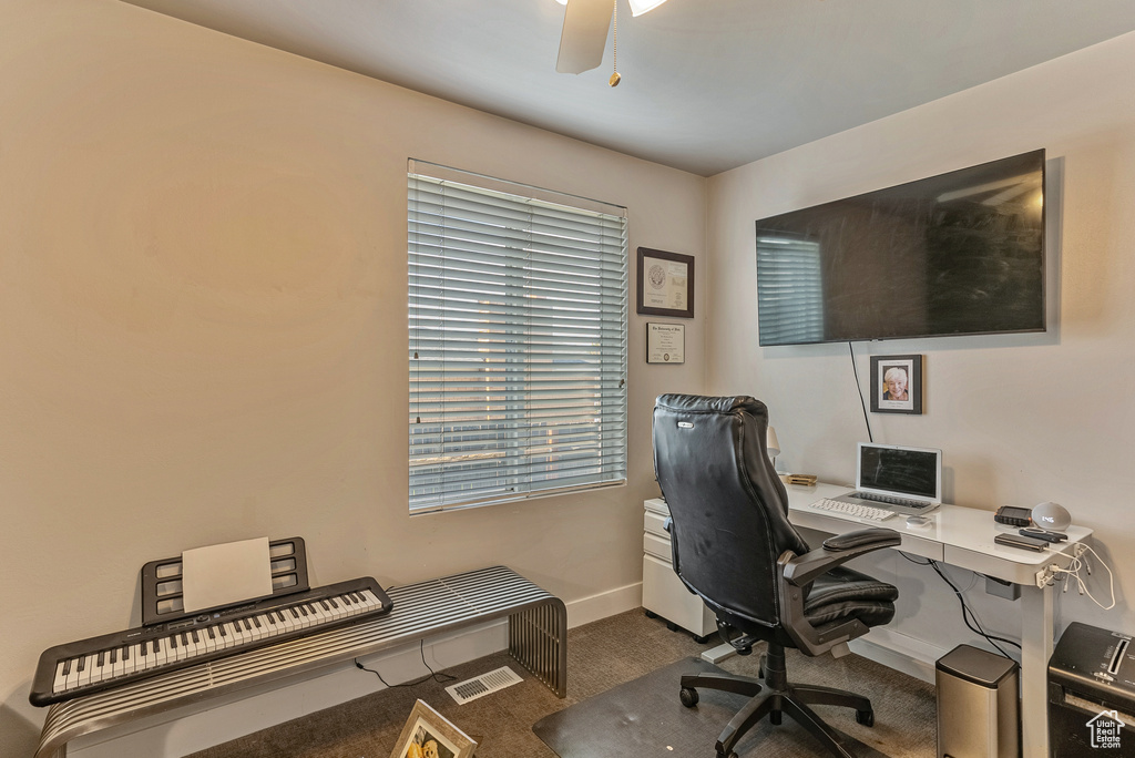 Home office featuring dark carpet and ceiling fan