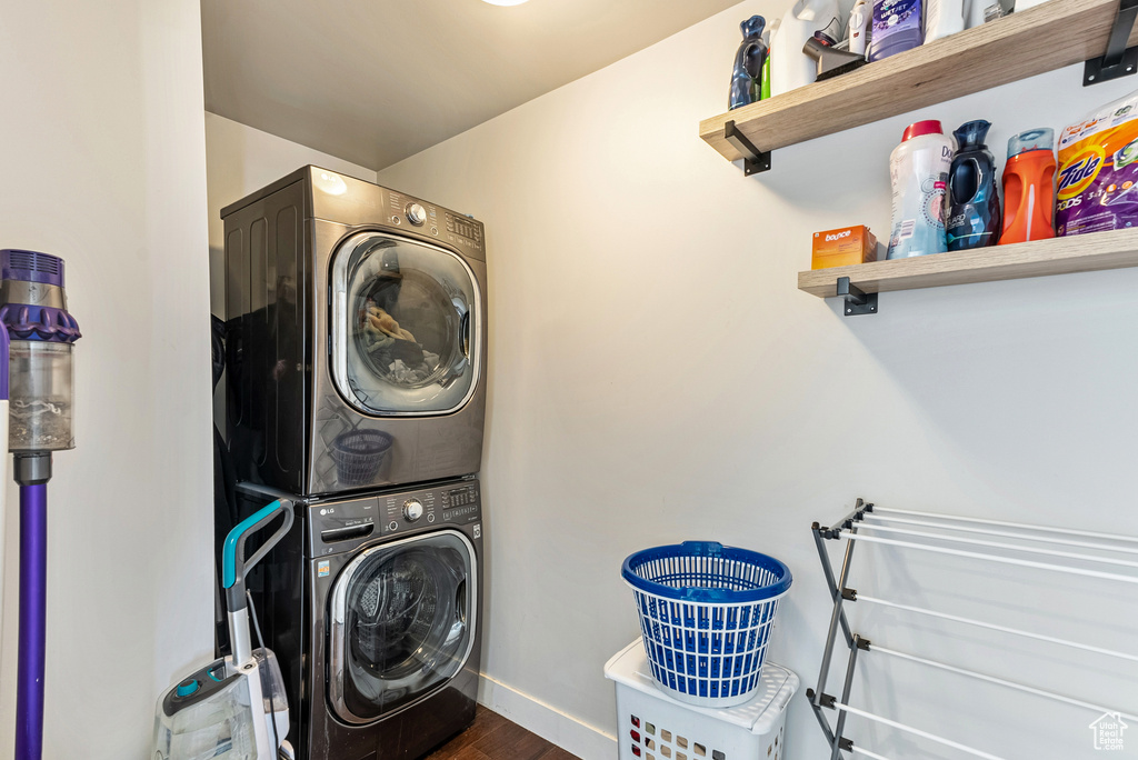 Clothes washing area with stacked washer and clothes dryer and dark hardwood / wood-style flooring