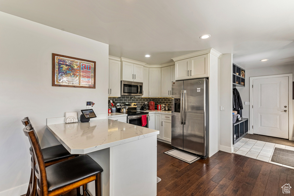 Kitchen featuring light wood-type flooring, stainless steel appliances, a kitchen bar, and kitchen peninsula