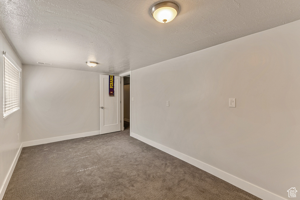 Spare room with a textured ceiling and dark carpet
