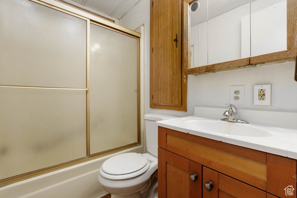 Full bathroom with enclosed tub / shower combo, large vanity, and toilet