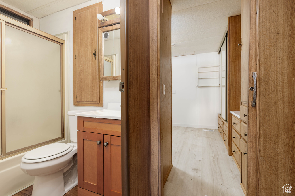Full bathroom featuring toilet, enclosed tub / shower combo, vanity, and hardwood / wood-style flooring