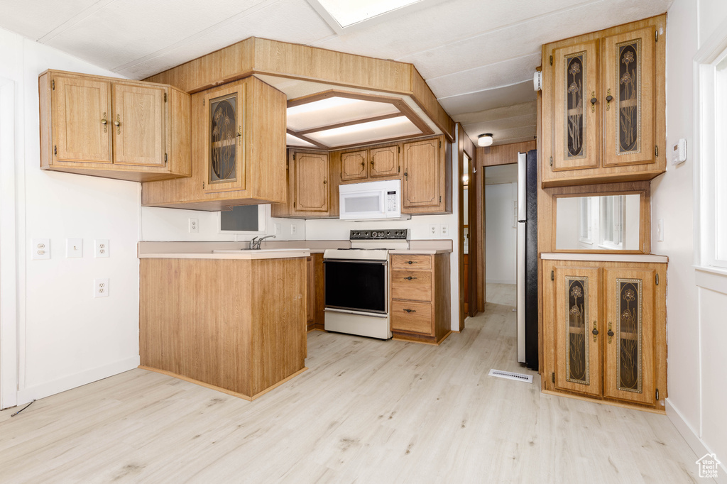 Kitchen with white appliances and light hardwood / wood-style flooring