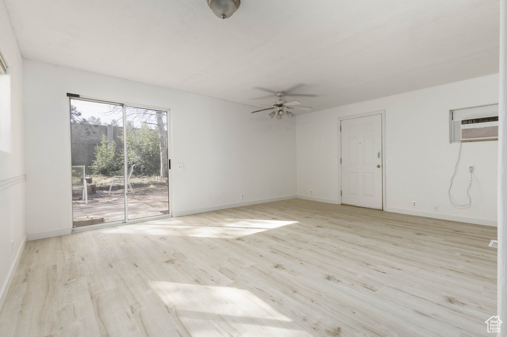 Unfurnished room with ceiling fan, light hardwood / wood-style flooring, and a wall mounted air conditioner