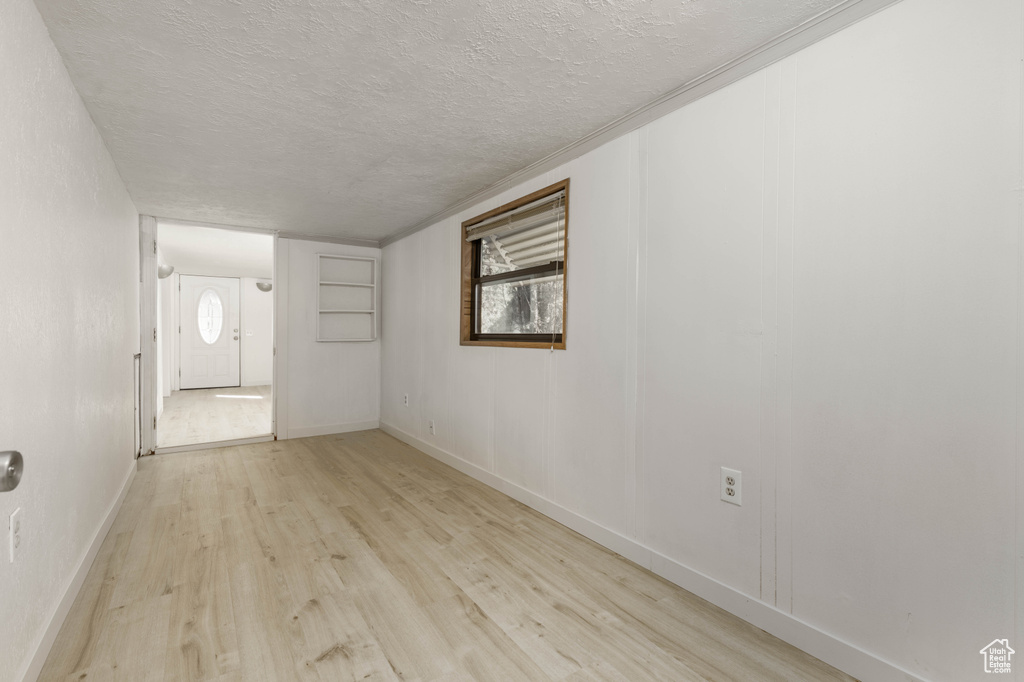 Unfurnished room with a textured ceiling and light wood-type flooring