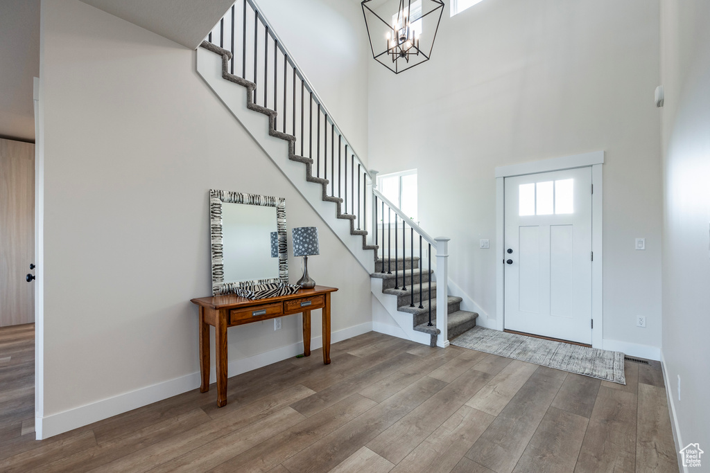 Foyer entrance with a high ceiling, hardwood / wood-style flooring, and an inviting chandelier