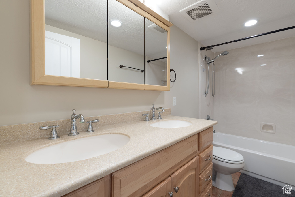 Full bathroom with bathing tub / shower combination, oversized vanity, dual sinks, and toilet