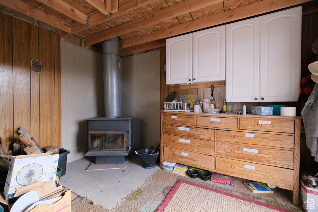 Interior space featuring a wood stove, wooden walls, and white cabinetry