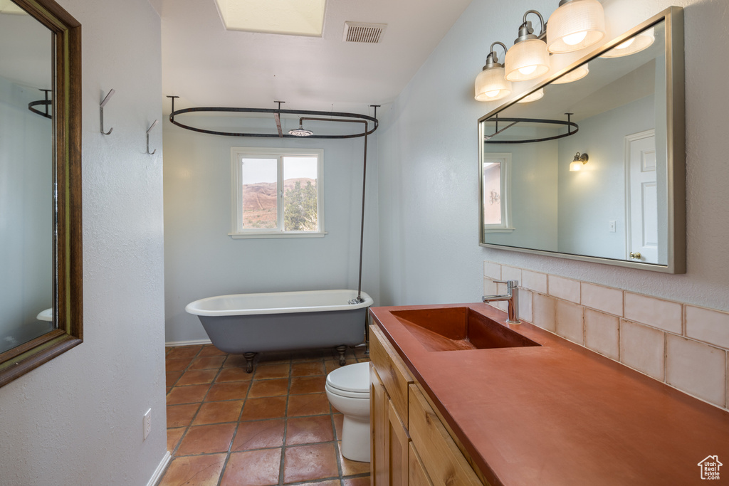 Bathroom with tile flooring, toilet, backsplash, and oversized vanity