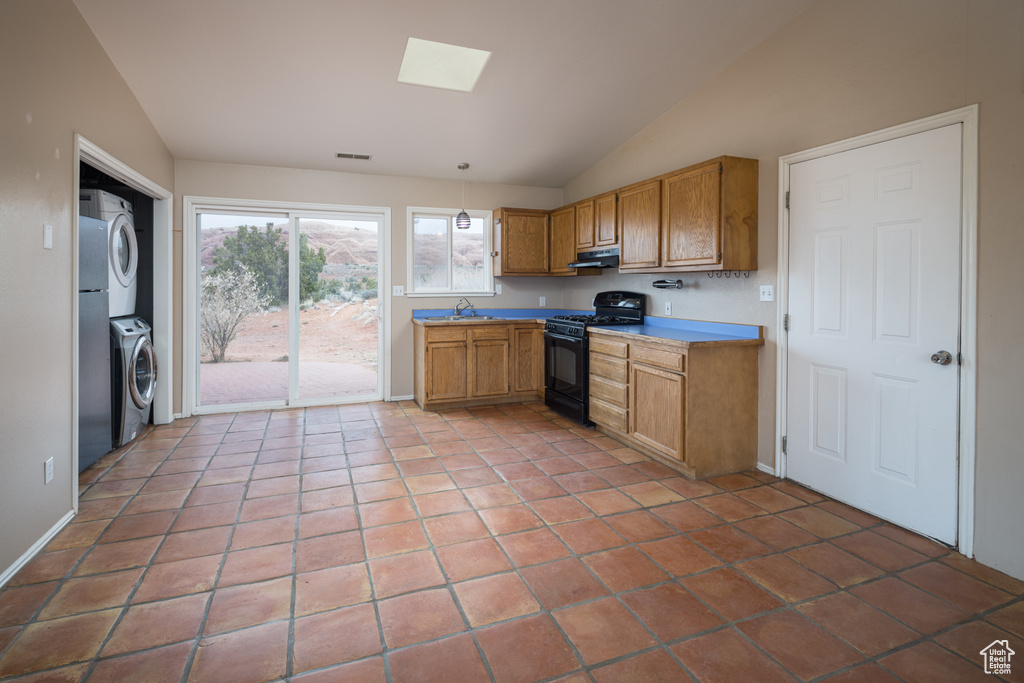Kitchen with stacked washer and clothes dryer, tile flooring, and black gas stove