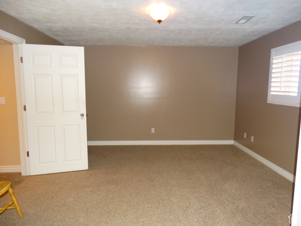 Spare room with a textured ceiling and light carpet
