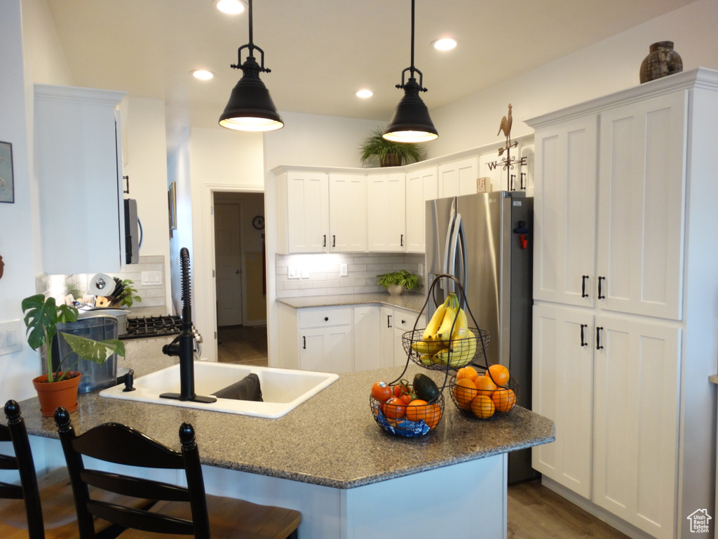 Kitchen with pendant lighting, white cabinets, backsplash, and light hardwood / wood-style floors