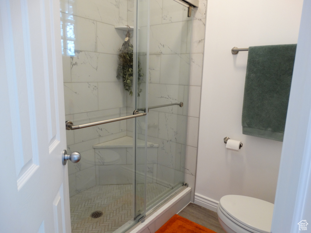 Bathroom with hardwood / wood-style floors, walk in shower, and toilet