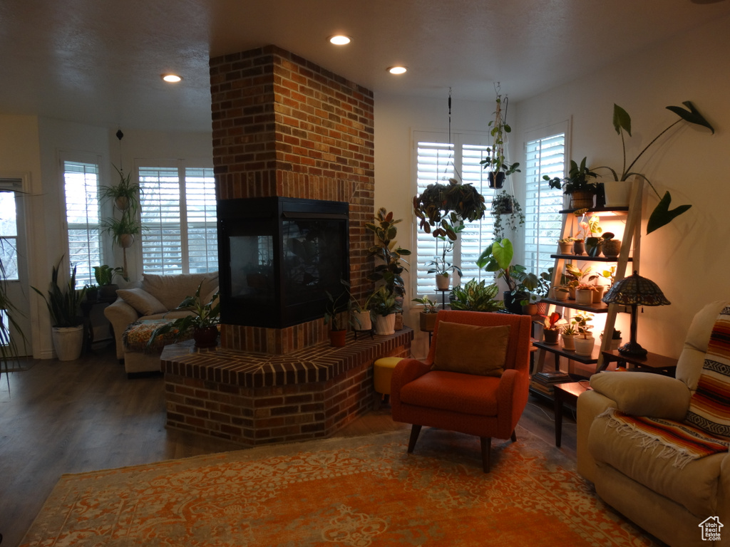 Living room with a brick fireplace, brick wall, and dark hardwood / wood-style floors