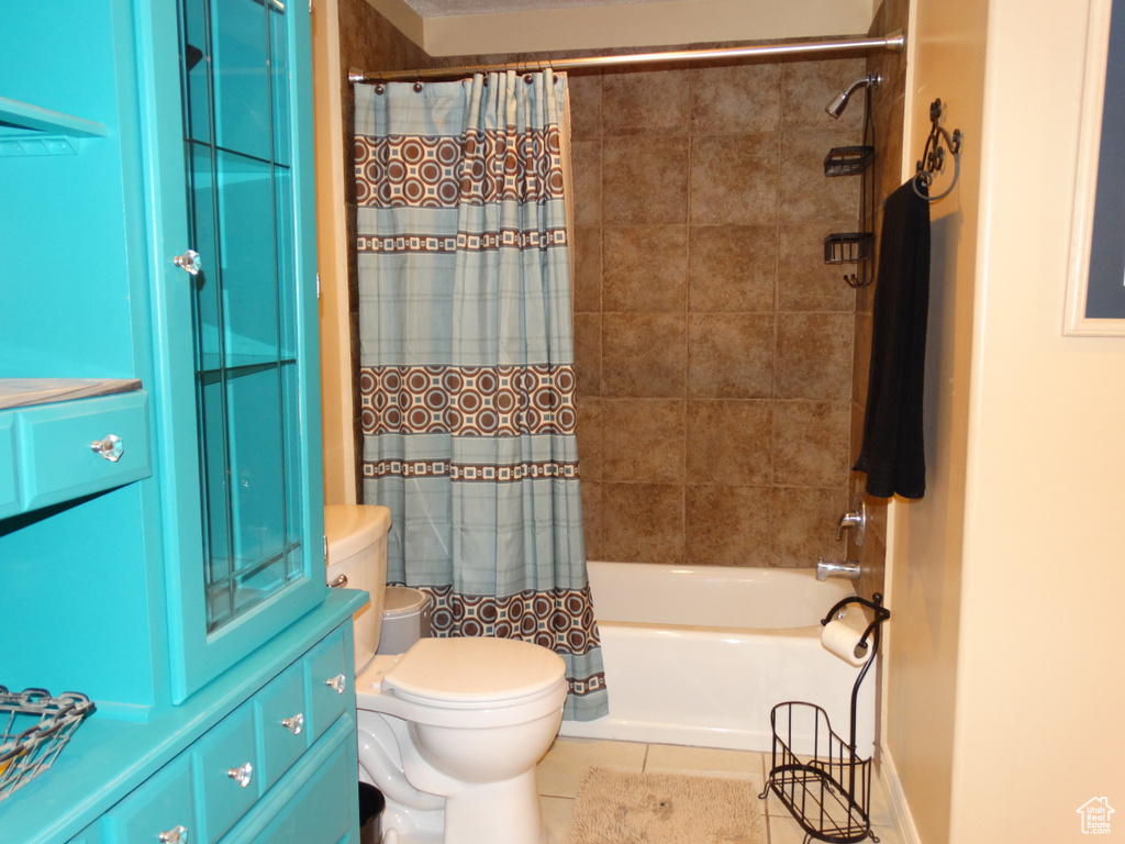 Bathroom featuring tile floors, shower / tub combo, and toilet