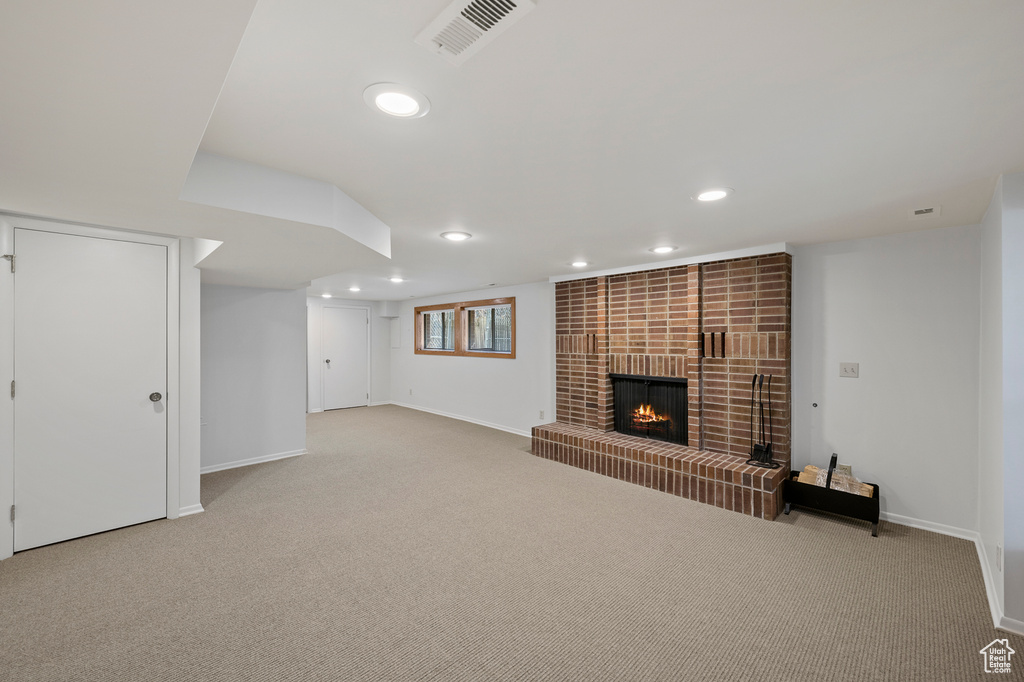 Unfurnished living room featuring a brick fireplace and light colored carpet
