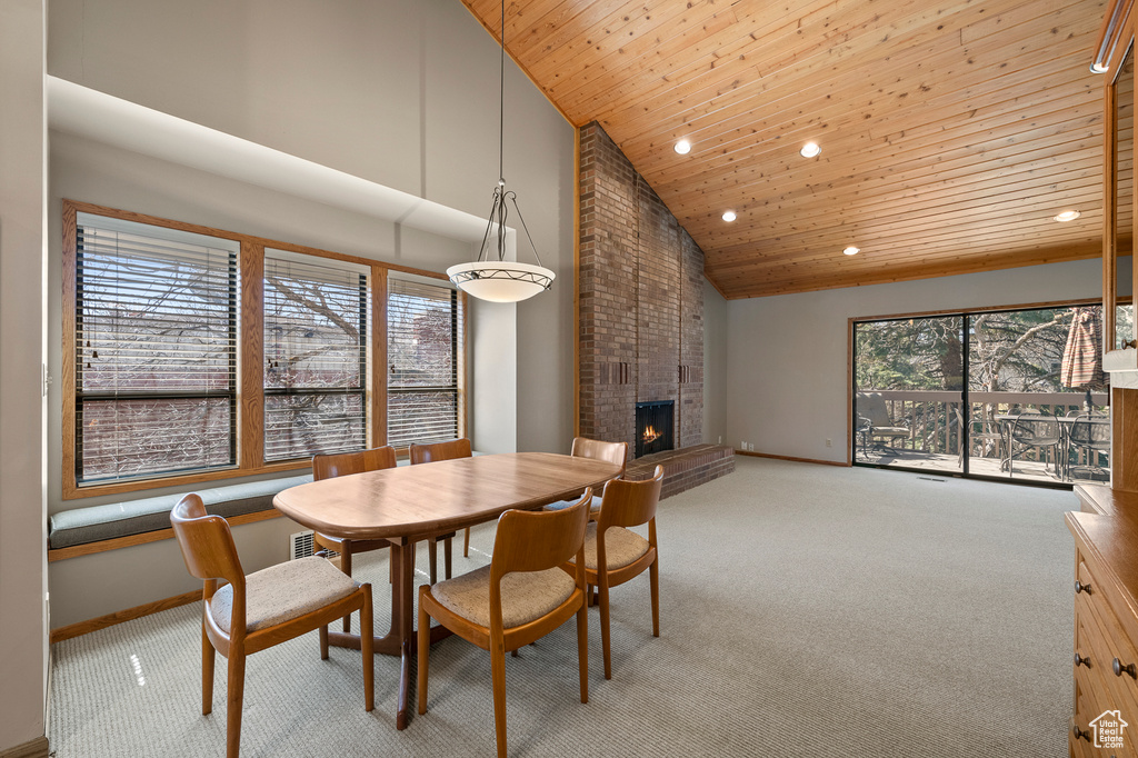 Carpeted dining area featuring a fireplace, brick wall, high vaulted ceiling, and wood ceiling