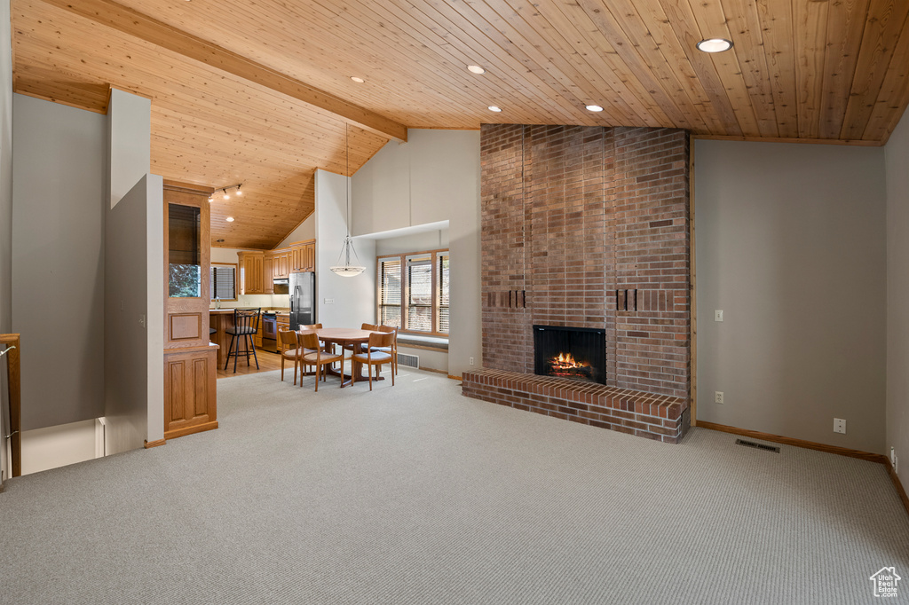 Living room featuring wooden ceiling, light carpet, high vaulted ceiling, brick wall, and a brick fireplace