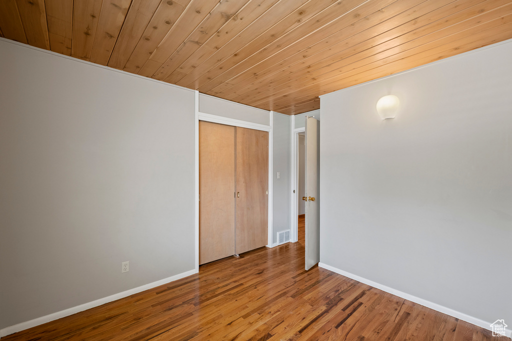Unfurnished bedroom with a closet, wooden ceiling, and hardwood / wood-style flooring