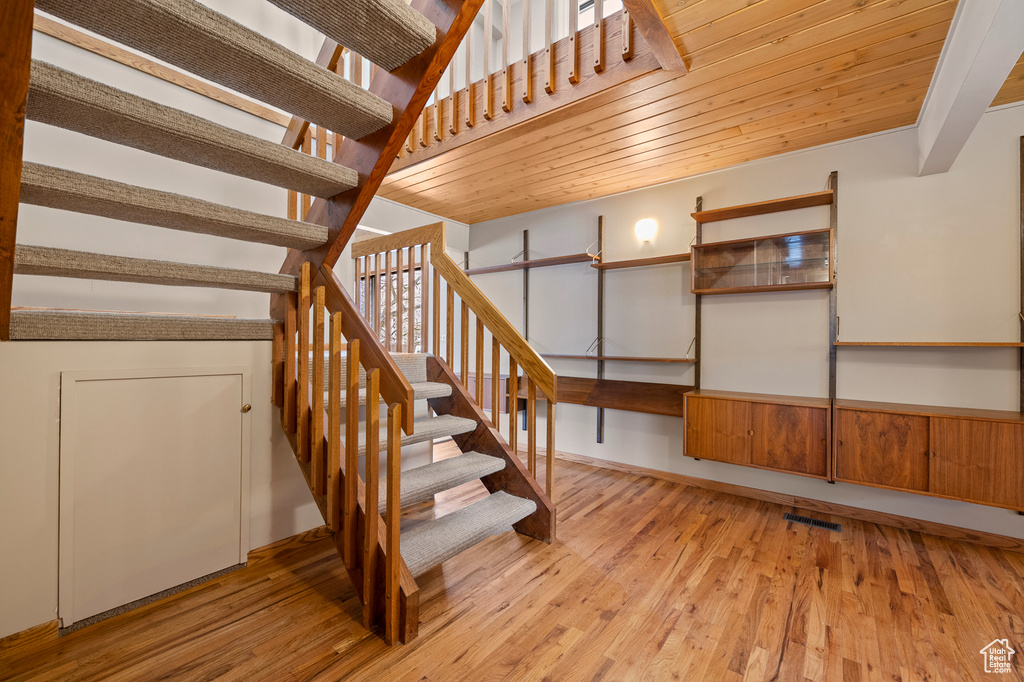 Staircase with wooden ceiling and light hardwood / wood-style flooring